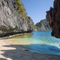 White sand cove enclosed by limestone cliffs at Hidden Beach, Matinloc Island