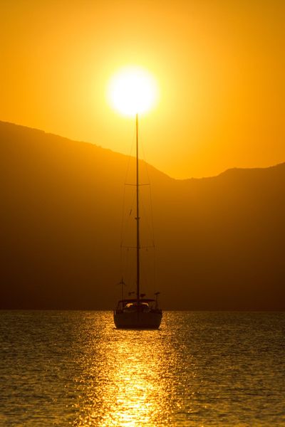 The yacht at anchor at sunset with hills behind