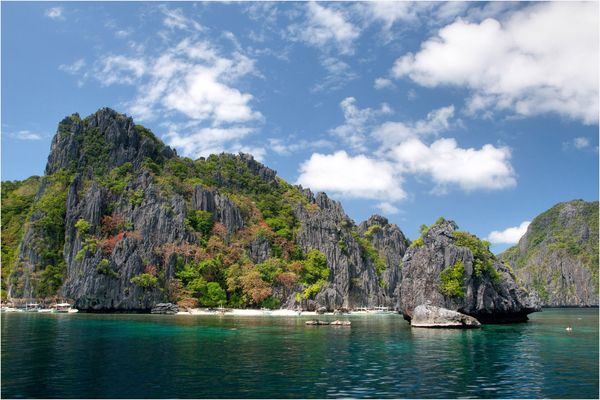 Karst cliffs of Shimizu Island with boats pulled up on the sand