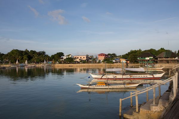 Bangkas moored in calm water off the San Vicente town waterfront in morning light