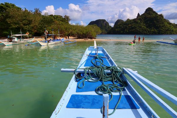 Approaching the Snake Island sandbar on a Tour B outrigger boat, with karst peaks behind