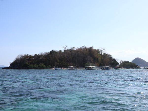 CYC Island seen from the water, with tour boats moored along its beach